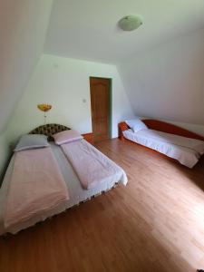 a bedroom with two beds and a wooden floor at Kamilla Kulcsoshaz in Sub Cetate