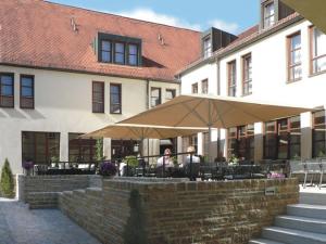 two people sitting under an umbrella in front of a building at Hotel Lamm in Höchberg