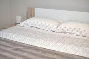 a white bed with two pillows on it at Family Retreat with Pool, BBQ & Green Escape by Destination GREEN Croatia in Praporčan +16 photos