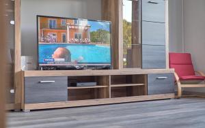 a television on a wooden entertainment center in a living room at Family Retreat with Pool, BBQ & Green Escape by Destination GREEN Croatia in Praporčan