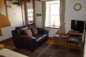 een woonkamer met een leren stoel en een televisie bij Engellie Cottage in Perranporth