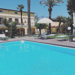 a swimming pool in front of a building with palm trees at VILLA LUCIA in Castellammare di Stabia