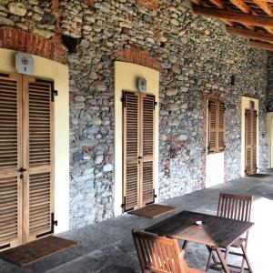 a wooden table and chairs in front of a stone building at Le 5 Frecce in Cavour