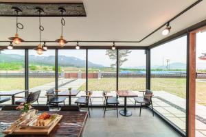 a room with tables and chairs and large windows at Gyeongju Hwarangroo in Gyeongju