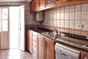a kitchen with wooden cabinets and a sink at Casa da Praça in Torre de Moncorvo