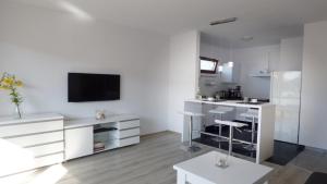 a white living room with a tv on a wall at Apartament Reda in Świnoujście