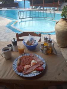Un plato de comida en una mesa cerca de una piscina. en Jack's Apartments, en Kefalos