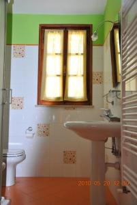 baño con lavabo y aseo y ventana en B&B La vecchia quercia Home Restaurant, en Fornovo di Taro