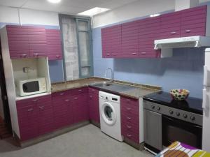 a kitchen with purple cabinets and a washing machine at Apartamento vinamar in Vinarós