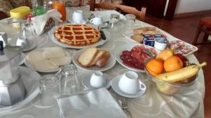 una mesa blanca cubierta con platos de desayuno en All'ombra degli Ulivi B&B en San Marcello