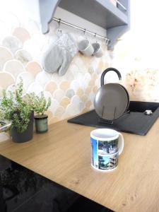 kubek kawy na drewnianym blacie z roślinami w obiekcie Apartament Pod Tężnią w mieście Głuchołazy