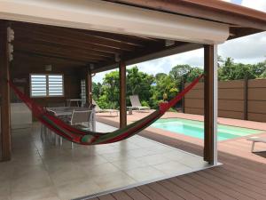 a hammock on a deck next to a swimming pool at Villa neuve de standing en bois avec piscine in Sainte-Anne