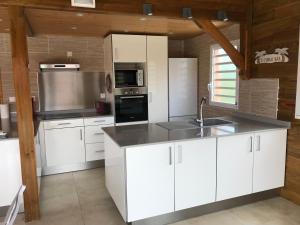 una cocina con armarios blancos y un aparato de acero inoxidable en Villa neuve de standing en bois avec piscine, en Sainte-Anne