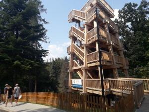 a wooden tree house with people walking around it at Apartament Pod Tężnią in Głuchołazy