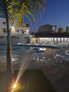 a pool with a table and chairs and a palm tree at Sibari Residence in Marina di Sibari
