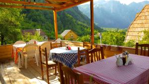 patio ze stołami i krzesłami z górami w tle w obiekcie Guesthouse "Gjin Thana" w mieście Theth