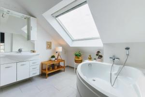 baño con bañera blanca grande y tragaluz en Zythogite Appartement 6 personnes avec jardin, bbq en Tintigny