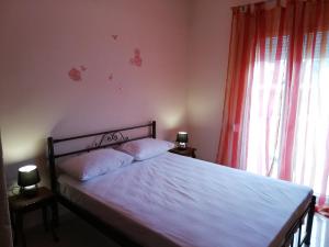 a bedroom with a bed with white sheets and red curtains at Aspa's Apartment in Kavala