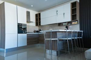 a kitchen with white cabinets and bar stools at Couple's Getaway in Is-Swieqi