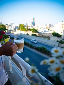 a person holding a cup of coffee on a balcony at Couple's Getaway in Is-Swieqi