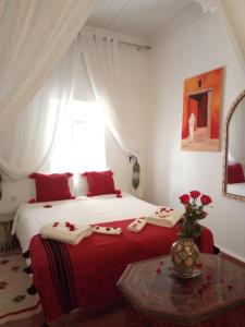 Un dormitorio con una cama roja y blanca y una mesa en Riad Etoile De Mogador, en Essaouira
