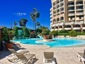 a swimming pool with chairs and a building at MyHome Riviera - Cannes Sea View Apartment Rentals in Cannes