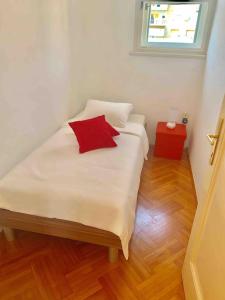 a white bed with a red pillow and a window at Split City Center Apartment in Split