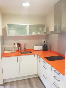 a kitchen with white cabinets and an orange counter top at Apartamento moderno Vielha centro in Vielha +8 photos