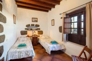 una camera da letto con due letti e una finestra di El Caserío de Güime Villa con Piscina Climatizada a San Bartolomé Altre 61 foto