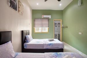 zwei Betten in einem Zimmer mit grünen Wänden in der Unterkunft Gunung View Homestay 10 to 12 pax near Sunway Tambun in Ipoh