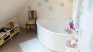 a bathroom with a white tub and a chair at Gîte Yves in Wihr-au-Val