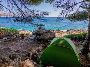 a green tent on a rocky beach next to the ocean at THE SEA CAVE CAMPING in Himare
