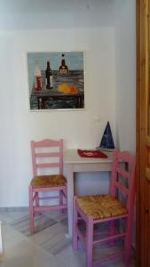 a table with two chairs and a painting on the wall at Zacharoula Rooms in Manganítis