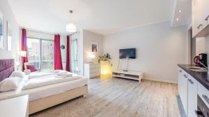 een witte slaapkamer met een bed en een televisie bij Sopot Residence - Sea Deluxe apartment A in Sopot