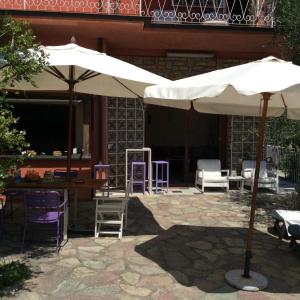 a patio with two white umbrellas and chairs and tables at Cinqueterre Alla Chetichella in Lerici