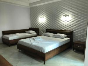 two beds in a bedroom with two lamps on the wall at Magnetiti Hotel in Ureki