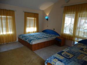 a bedroom with two beds and two windows at Kapka Apartments in Kiten