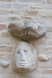 Una statua di pietra di una donna con un fungo in testa di Casa della Strega a Montegiorgio