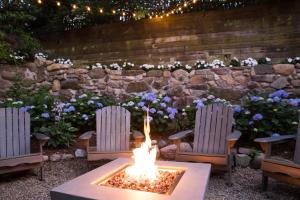 una hoguera en un patio con 2 sillas y una pared de piedra en Carlisle House Inn, en Nantucket