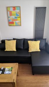 a black couch with two yellow pillows and a coffee table at Victoria House in Exeter