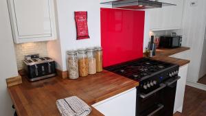 cocina con fogones y encimera roja en Victoria House en Exeter