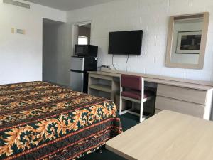 a hotel room with a bed and a desk and a television at Super Lodge Motel El Paso in El Paso