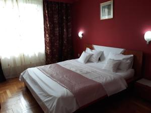 a bedroom with a white bed with a red wall at Pensiunea Sydney in Timişoara