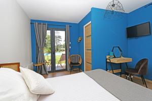 1 dormitorio con paredes azules, 1 cama y escritorio en L Esprit du Clain chambres d hôtes BandB de standing proches du Futuroscope Golf et Lac de St Cyr, en Naintré