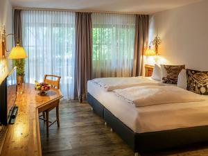 um quarto de hotel com uma cama grande e uma secretária em Mäser´s Allgäuherz em Wiggensbach