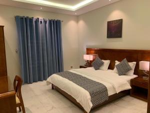 1 dormitorio con 1 cama grande y cortinas azules en Anan Suites, en Dammam