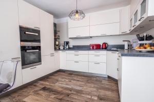 una cucina con armadietti bianchi e pavimenti in legno di Moderne Souterrain-Wohnung ad Anif Altre 4 foto