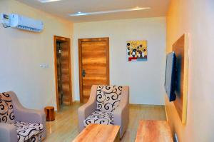 a room with two chairs and a table and a tv at Lit Suites in Abuja