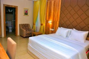 a bedroom with a large bed and a chair at Lit Suites in Abuja