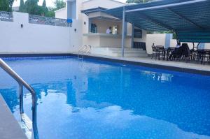 a large blue swimming pool with tables and chairs at Lit Suites in Abuja